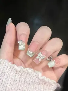 Detailed close-up of handmade press-on nails with silver butterfly and pearl decorations