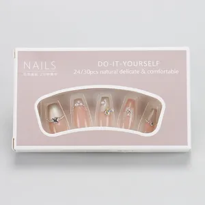 Macro view of pink gradient press-on nails with butterfly charms and pearl details
