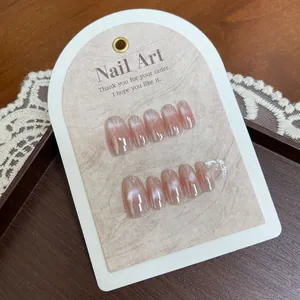Short oval cat-eye press-on nails in nude pink gradient on a textured display card