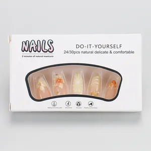 Close-up of DIY press-on nails with 3D floral designs and pearls in retail packaging