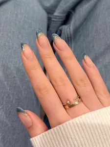 Dettaglio macro di unghie a mandorla con punte glitter blu e linee d'oro d'arte