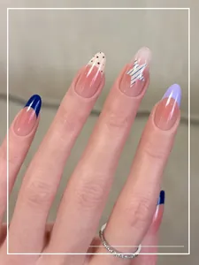 Detail of press-on nails with navy French tips, pink gradient stars, and white polka dots