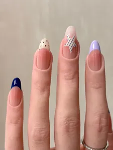 Detailed view of almond-shaped press-on nails featuring blue stripes and star patterns