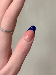 Detailed view of blue French tip press-on nails with shiny finish on oval shape
