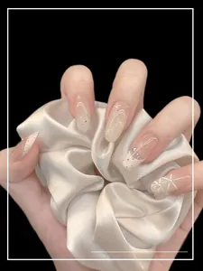 Macro detail of nude press-on nails with 3D white bows, pearls, and rhinestone accents