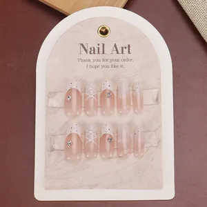 Detail of nude pink press-on nails with pearls, rhinestones and chic bow decorations