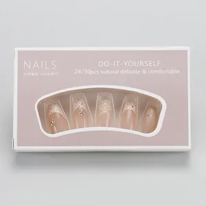 Detail of almond-shaped press-on nails with nude pink base, black dots, and pearls