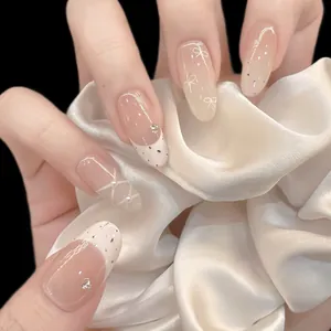 Elegant nude pink almond press-on nails with white French tips and bow decorations