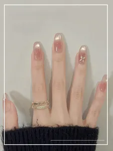 Detail of pink cat-eye press-on nails in oval shape with 3D butterfly rhinestone accents