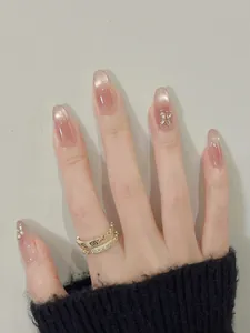Macro detail of cat eye press-on nails with butterfly charms and pearl accents