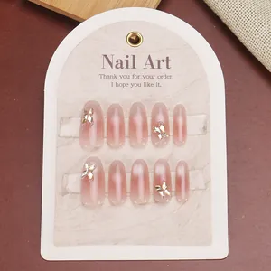 Pink gradient almond press-on nails with 3D metal bows on high-quality display card