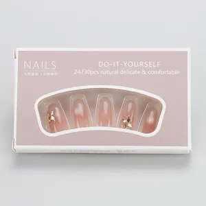 Detail of nude pink gradient press-on nails with golden butterfly in a windowed box