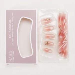 Detail of gradient pink press-on nails with butterfly rhinestones and packaging