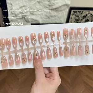 Matte cat-eye press-on nails with nude pink gradient and 3D golden bow accents