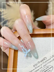Detail of almond cat eye nails with blue gradient bows and 3D glass bead accents