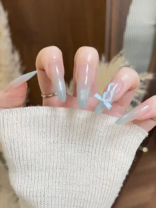 Detail shot of long almond press-on nails with blue cat-eye gradient and 3D bow