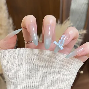 Long almond cat-eye press-on nails with blue gradient finish and 3D bow accent