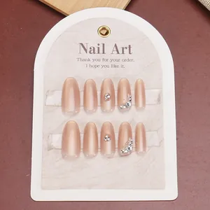 Handmade cat-eye press-on nails in nude pink with rhinestone accents and glitter finish