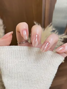 Primo piano di unghie finte ovali sfumate rosa nudo effetto aurora indossate su una mano con luce soffusa