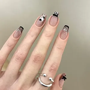 Short coffin press-on nails with nude gradient, black French tips, bows, and heart designs