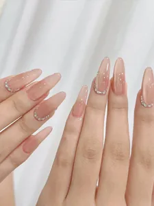 Close-up of almond-shaped gradient pink press-on nails with silver glitter crescent detail