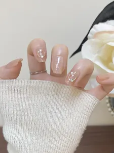 Short square press-on nails in nude pink with glitter, pearls, and gold ring accents
