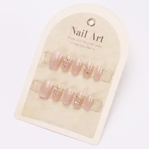 Short pink cat eye press-on nails with pearls and rhinestones on display card