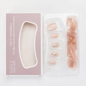 Detail of nude pink press-on nails set in elegant purple packaging with pearl accents