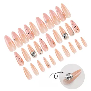 Detail view of almond press-on nails with pink gradient, rhinestones and 3D textures