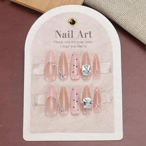 Long almond press-on nails in nude pink with rhinestones, black polka dots and French tip