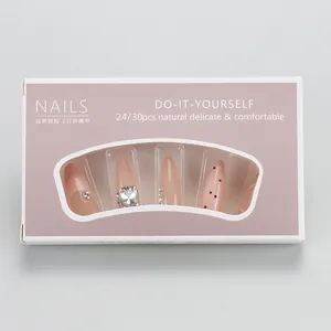 Macro detail of almond press-on nails with pink gradient, rhinestones and black dots