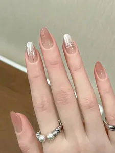 Detail of pink gradient press-on nails with 3D bow accent and subtle shimmer