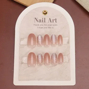Pink gradient press-on nails set with silver glitter and bow patterns on marble card