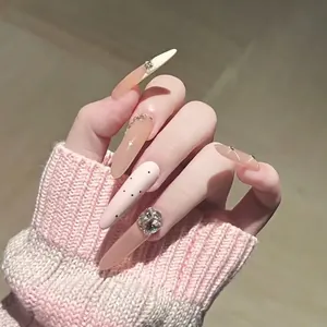 Elegant long stiletto nude pink press-on nails with rhinestones and black polka dots