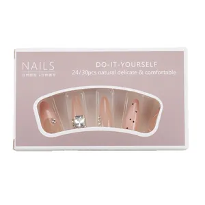Long almond press-on nails in nude pink with rhinestones and black polka dots