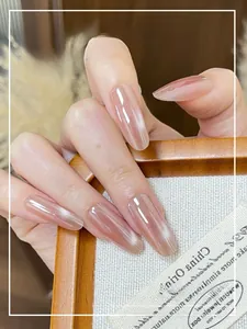 Macro shot of long almond pink cat-eye press-on nails displayed on a wooden tray