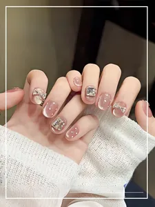 Détail de faux ongles œil-de-chat roses avec nœuds papillon, perles et strass