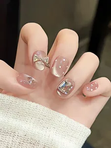 Détail d'ongles faits main avec effet œil de chat rose nude et nœud champagne 3D élégant