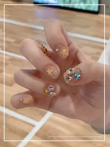 Detail of short press-on nails featuring yellow stars and colorful rhinestones