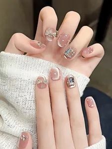 Vue macro de faux ongles œil-de-chat rose poudré avec nœud argenté et cristaux brillants