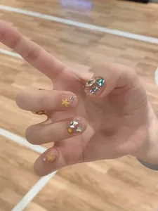 Macro detail of short press-on nails featuring yellow stars and multi-colored rhinestones