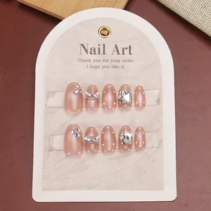 Détail d'ongles rose œil de chat avec nœud en métal, strass et perles élégantes