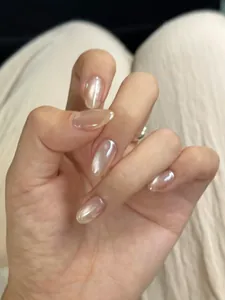 Detail of short oval press-on nails with nude pink cat-eye shimmer on silk fabric