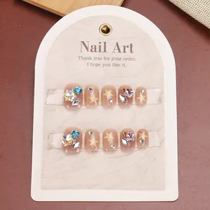 Short square press-on nails with yellow stars and sparkling rhinestones on nude base