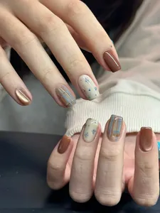 Nahaufnahme von braun-blauen Katzenaugen-Nägeln mit Blumen- und Karomuster in kurzer Quadratform