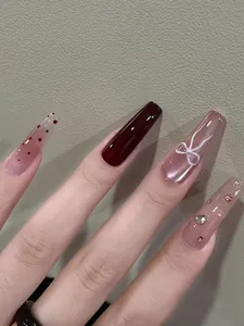 Detail van lange coffin nagels met cat-eye finish, parelstrikje en strass steentjes