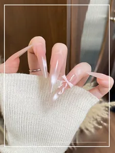 Detail of long stiletto press-on nails with pink gradient and 3D white ribbon bow