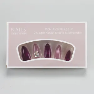 Close-up of purple cat eye press-on nails set with rhinestone accents in retail packaging