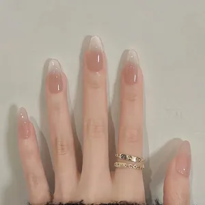 Press-on nails in nude pink gradient with glitter finish on hand wearing a ring
