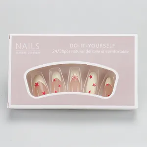 Detail of pink press-on nails set featuring red star and bow designs in retail packaging